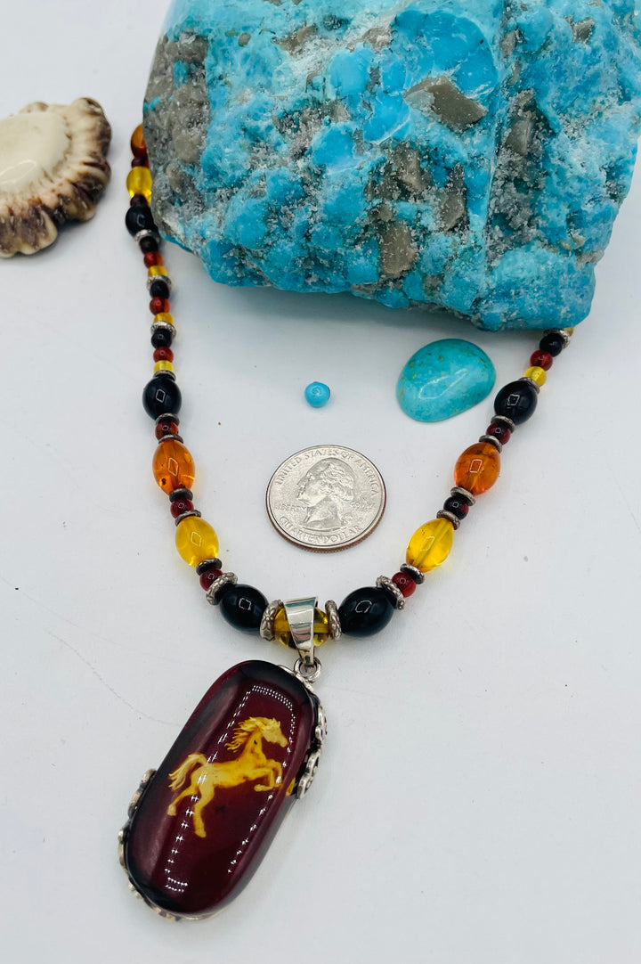 Beaded Baltic amber and sterling silver necklace featuring a Baltic amber and sterling silver pendent with a carved horse reverse cameo. U.S. quarter for size reference. Available only from Rockstar Cowgirl online or in store in Cody, Wyoming.