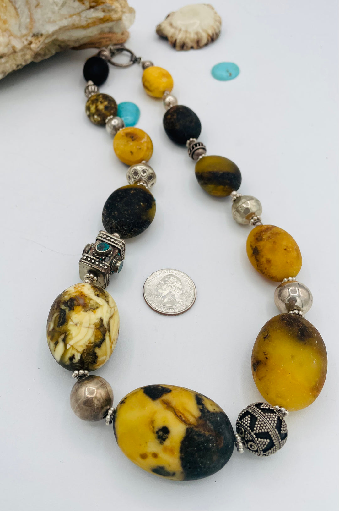 Chunky beaded necklace featuring Baltic amber, repousse beads with turquoise inlay, and sterling silver beads. U.S. quarter for size reference. Available only from Rockstar Cowgirl online or in store in Cody, Wyoming.