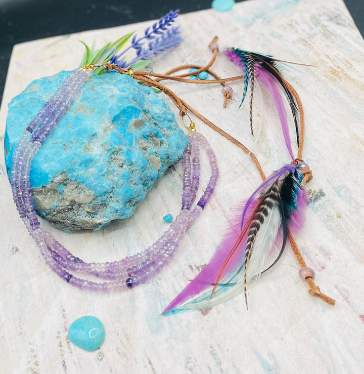 3 strand hatband or necklace of shaded amethyst with gold accents and finished with feathers, leather lace and a slide bead for fit. Available only from Rockstar Cowgirl online or in store in Cody, Wyoming.