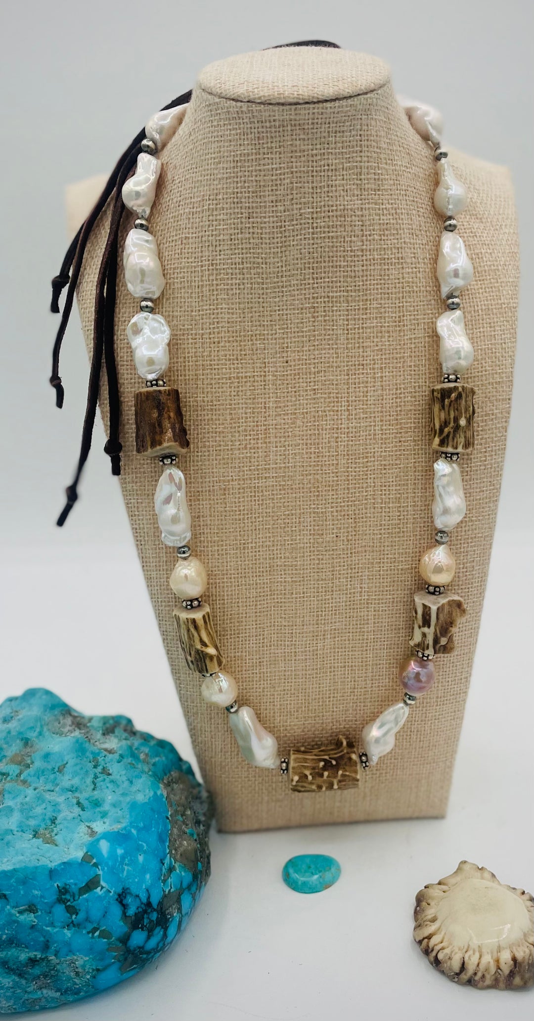 Adjustable beaded hattband featuring white flameball baroque pearls, textured deer antler, sterling silver beads, and finished with deer lace in the back. Available only from Rockstar Cowgirl online or in store in Cody, Wyoming.