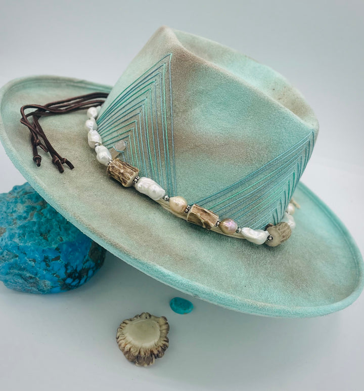 Adjustable beaded hattband featuring white flameball baroque pearls, textured deer antler, sterling silver beads, and finished with deer lace in the back. Available only from Rockstar Cowgirl online or in store in Cody, Wyoming.