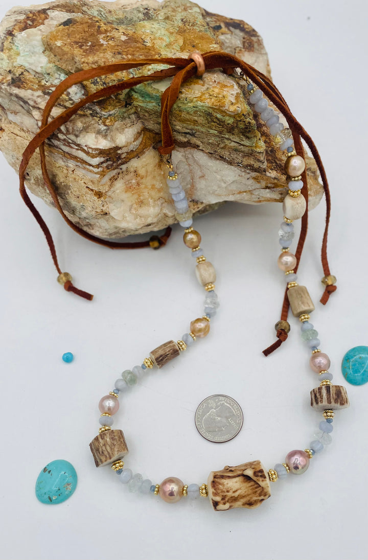 Adjustable beaded hatband featuring blue lace agate, aquamarine, glass crystals, gold details, baroque natural luster pearls, deer antler beads, and finished with deer lace in the back. U.S. quarter for size reference. Available only from Rockstar Cowgirl online or in store in Cody, Wyoming.