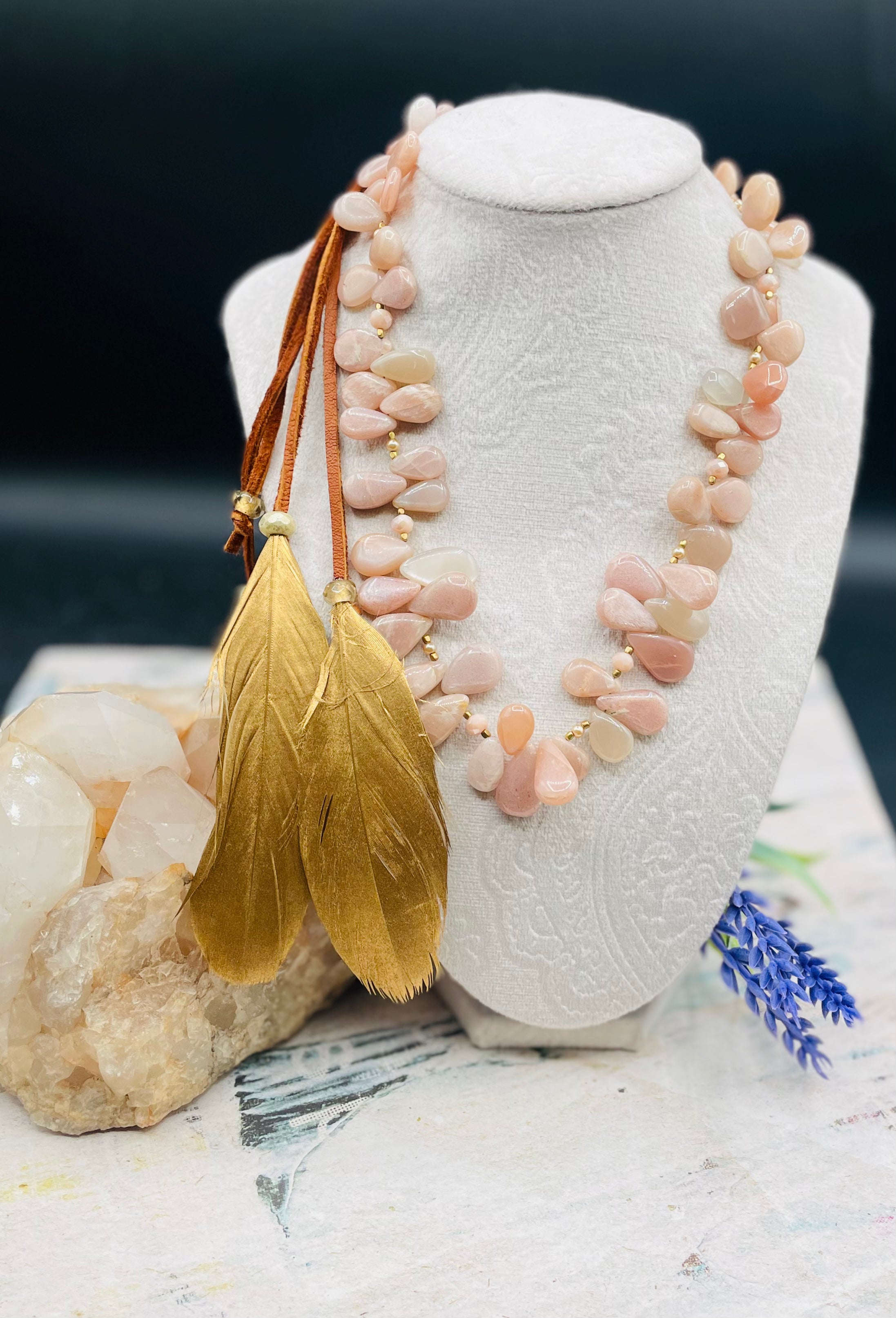 Creamy sunstone hatband or necklace with glass pearls, mauve crystals, and bronze sprinkled throughout finished with gold painted feathers, deer lace and slide bead for fit. Available only from Rockstar Cowgirl online or in store in Cody, Wyoming.