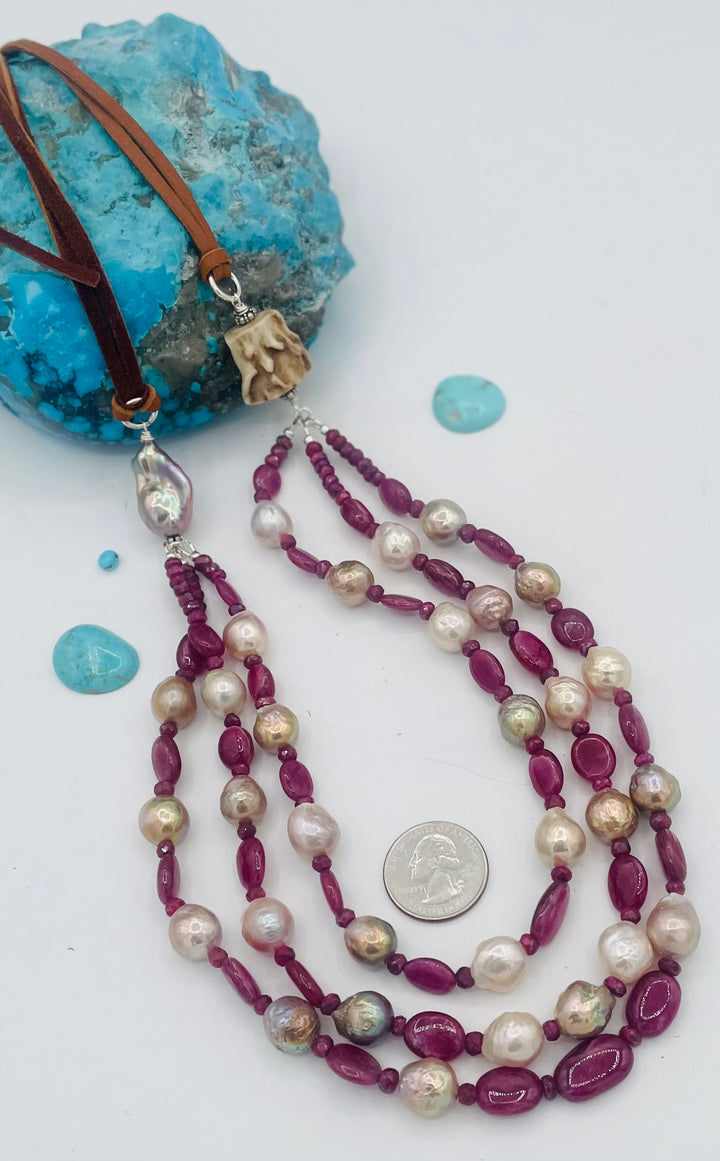Adjustable 3 strand necklace featuring ruby, Edison pearls, flameball baroque pearl, textured deer antler bead, and finished with deer lace. U.S. quarter for size reference. Available only from Rockstar Cowgirl online or in store in Cody, Wyoming.