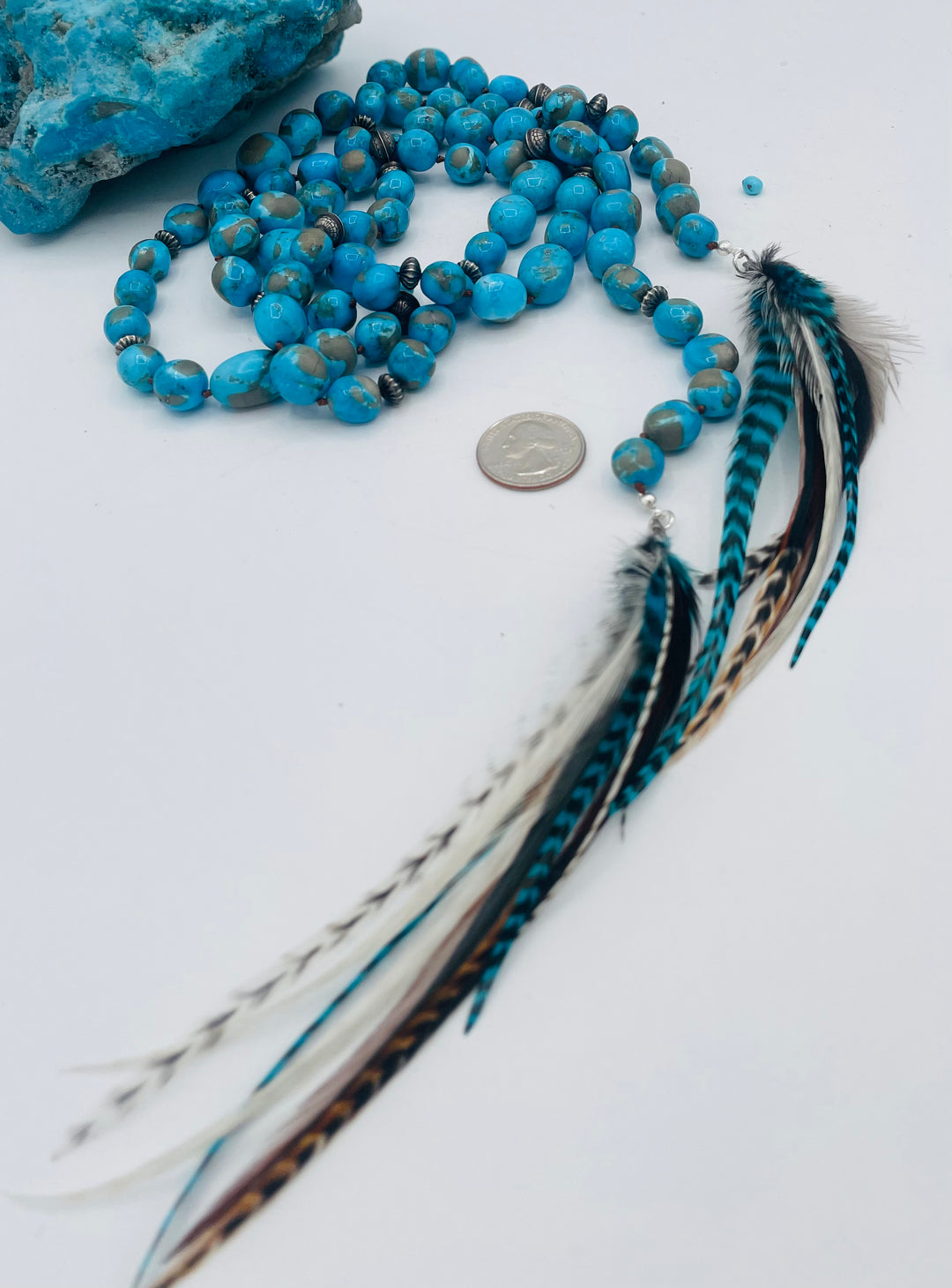 Silk knotted lariat featuring Ithaca peak turquoise, sterling silver beads, and feather tassels. U.S. quarter for size reference. Available only from Rockstar Cowgirl online or in store in Cody, Wyoming.