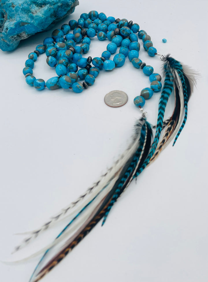 Silk knotted lariat featuring Ithaca peak turquoise, sterling silver beads, and feather tassels. U.S. quarter for size reference. Available only from Rockstar Cowgirl online or in store in Cody, Wyoming.