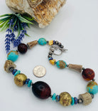 Chunky necklace featuring Baltic amber, Kingman turquoise, African bronze beads, large deer antler beads, and sterling silver Navajo pearl beads. U.S. quarter for size reference. Available only from Rockstar Cowgirl online or in store in Cody, Wyoming.