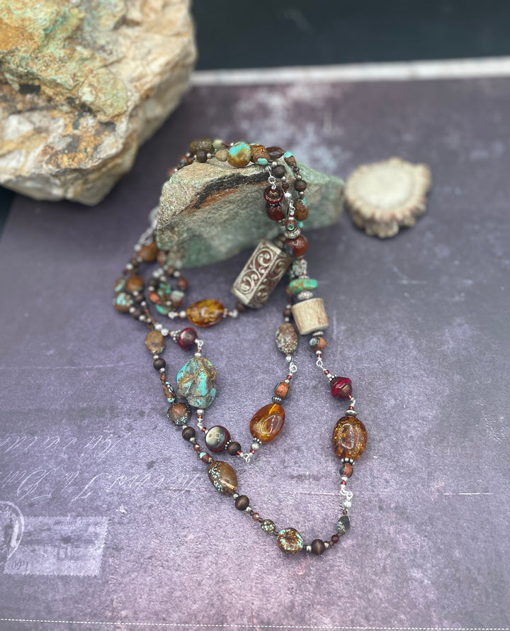 Long silk knotted and wire wrapped treasure necklace featuring #8 turquoise, Baltic amber, red travertine Czech beads, abalone inlaid wood beads, garnets, sterling silver beads, and deer antler beads and nuggets. Available only from Rockstar Cowgirl online or in store in Cody, Wyoming.