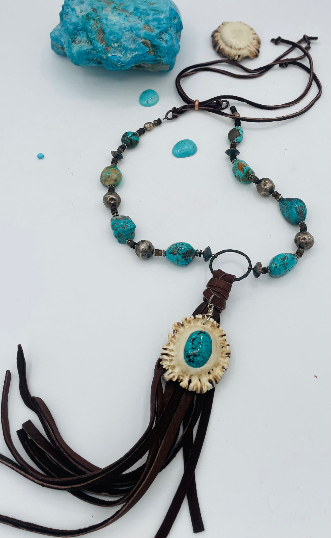 Adjustable beaded necklace featuring Kingman turquoise, hessonite garnet, vintage sterling silver, deer lace tassel with deer antler pendent, and finished with deer lace in the back. Available only from Rockstar Cowgirl online or in store in Cody, Wyoming.