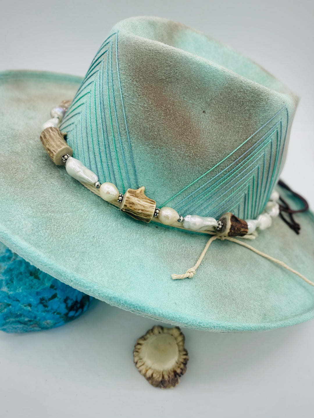 Adjustable beaded hattband featuring white flameball baroque pearls, textured deer antler, sterling silver beads, and finished with deer lace in the back. Available only from Rockstar Cowgirl online or in store in Cody, Wyoming.