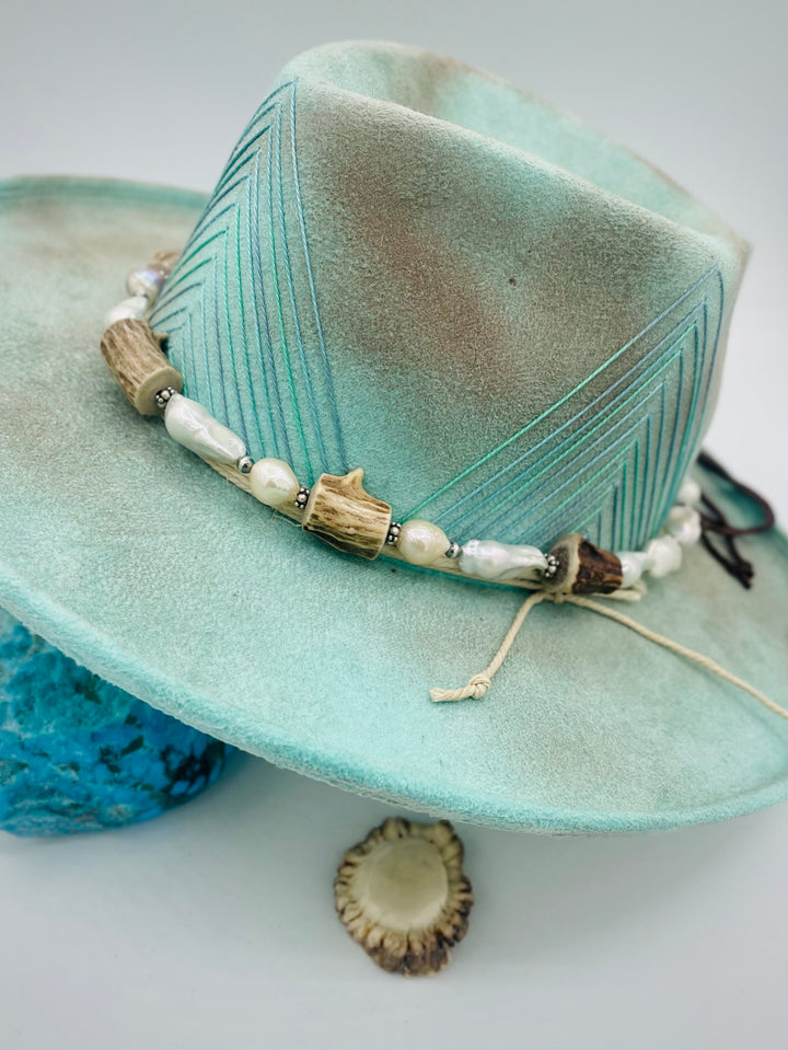 Adjustable beaded hattband featuring white flameball baroque pearls, textured deer antler, sterling silver beads, and finished with deer lace in the back. Available only from Rockstar Cowgirl online or in store in Cody, Wyoming.