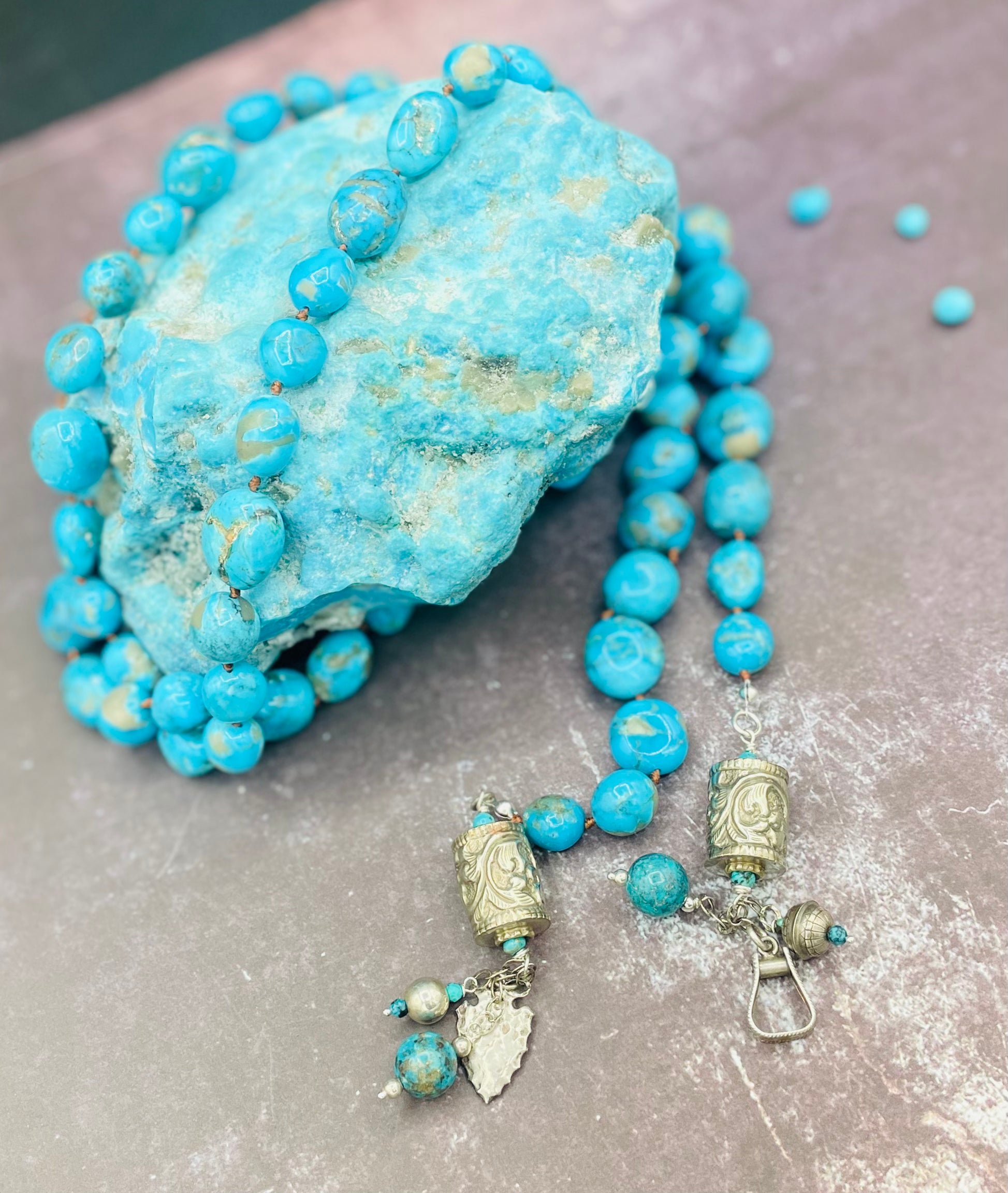 Ithaca peak turquoise silk knotted lariat with repousse beads and vintage sterling silver charms on the tails. Available only from Rockstar Cowgirl online or in store in Cody, Wyoming.