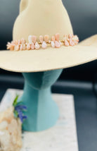 Creamy sunstone hatband or necklace with glass pearls, mauve crystals, and bronze sprinkled throughout finished with gold painted feathers, deer lace and slide bead for fit. Available only from Rockstar Cowgirl online or in store in Cody, Wyoming.