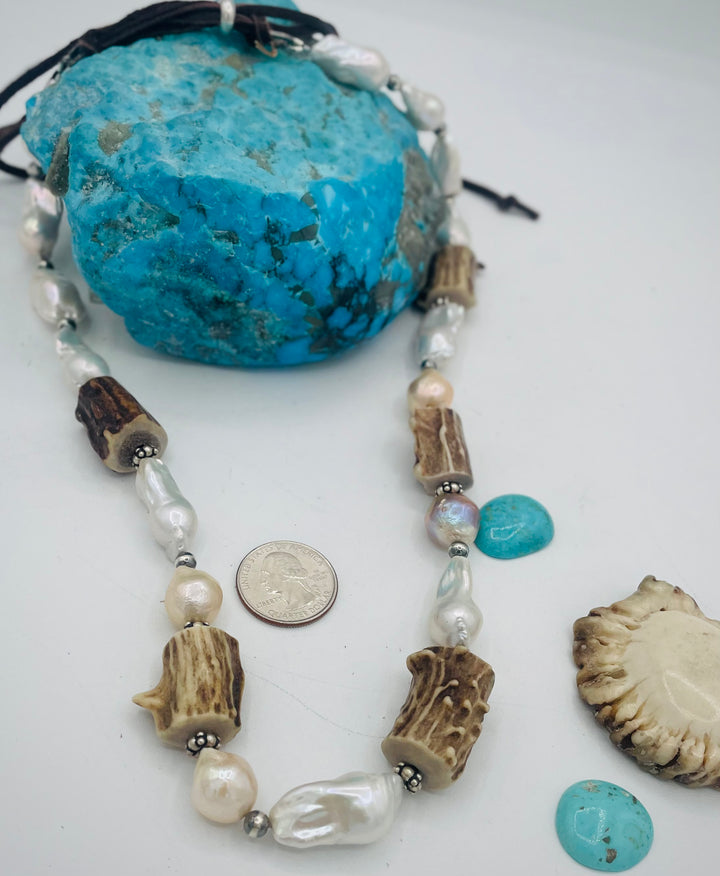 Adjustable beaded hattband featuring white flameball baroque pearls, textured deer antler, sterling silver beads, and finished with deer lace in the back. U.S. quarter for size reference. Available only from Rockstar Cowgirl online or in store in Cody, Wyoming.