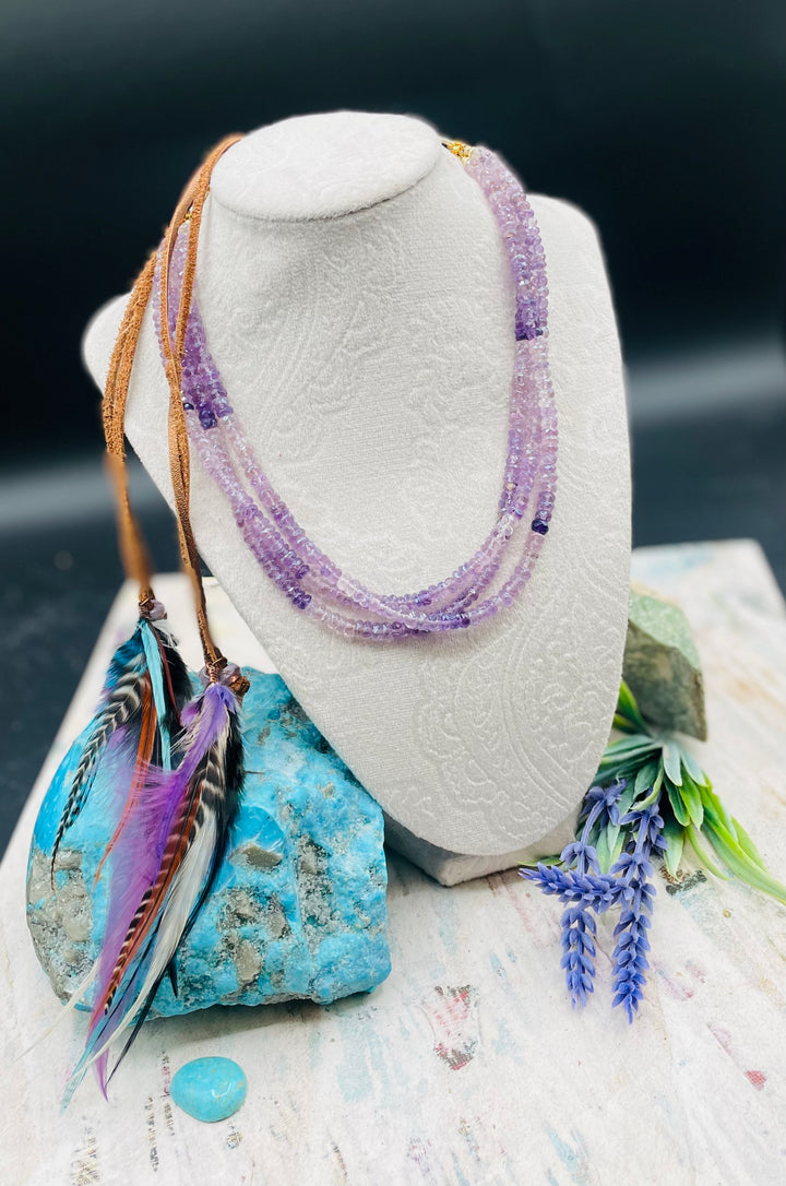 3 strand hatband or necklace of shaded amethyst with gold accents and finished with feathers, leather lace and a slide bead for fit. Available only from Rockstar Cowgirl online or in store in Cody, Wyoming.