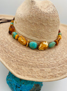 Adjustable beaded hatband featuring Baltic amber slabs, Kingman turquoise nuggets, sterling silver Navajo pearls beads and finished with deer leather and slide bead. Available only from Rockstar Cowgirl online or in store in Cody, Wyoming.