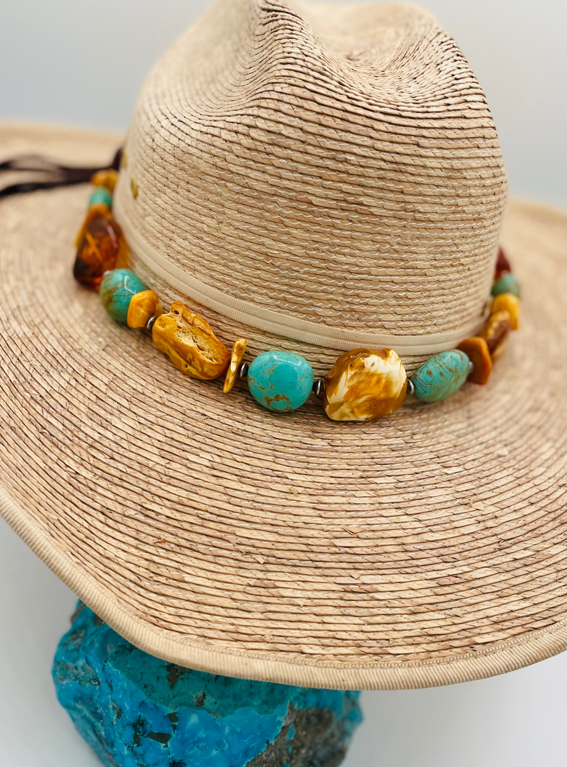Adjustable beaded hatband featuring Baltic amber slabs, Kingman turquoise nuggets, sterling silver Navajo pearls beads and finished with deer leather and slide bead. Available only from Rockstar Cowgirl online or in store in Cody, Wyoming.
