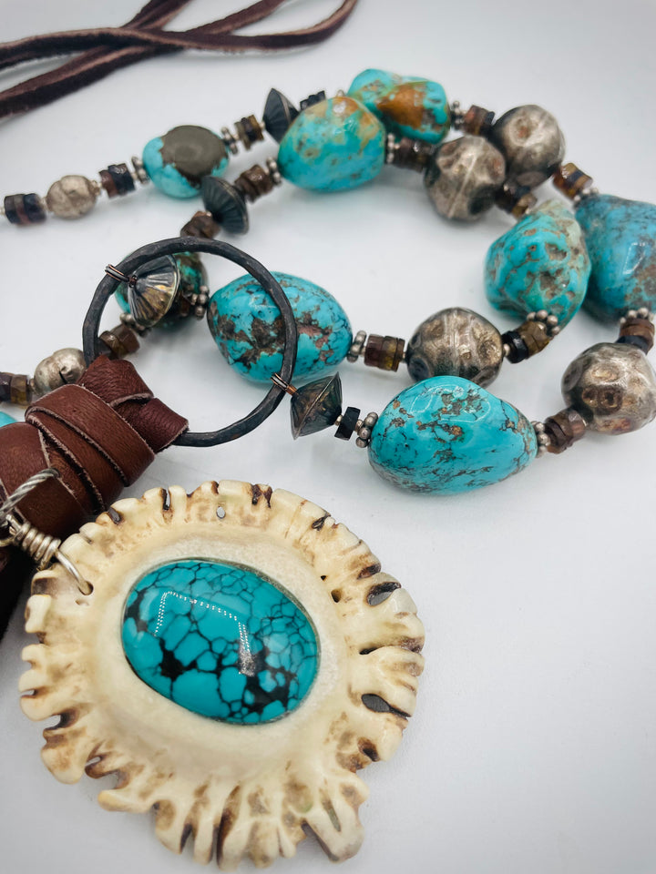 Adjustable beaded necklace featuring Kingman turquoise, hessonite garnet, vintage sterling silver, deer lace tassel with deer antler pendent, and finished with deer lace in the back. Available only from Rockstar Cowgirl online or in store in Cody, Wyoming.