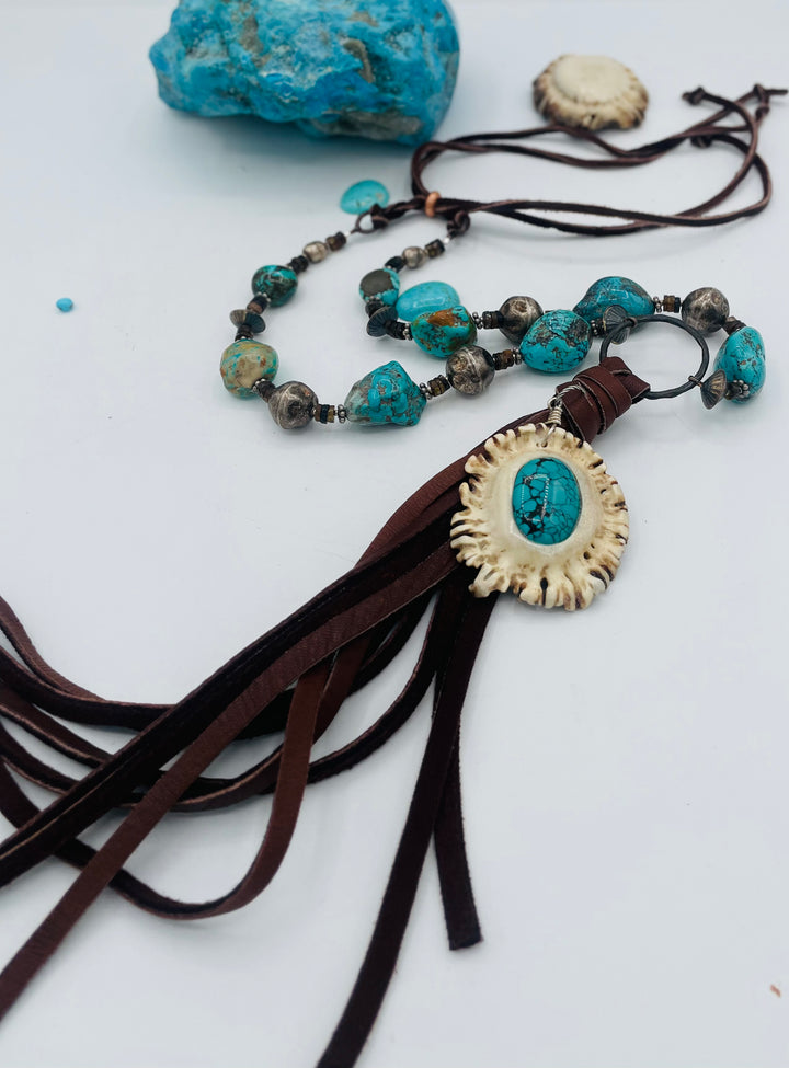 Adjustable beaded necklace featuring Kingman turquoise, hessonite garnet, vintage sterling silver, deer lace tassel with deer antler pendent, and finished with deer lace in the back. Available only from Rockstar Cowgirl online or in store in Cody, Wyoming.