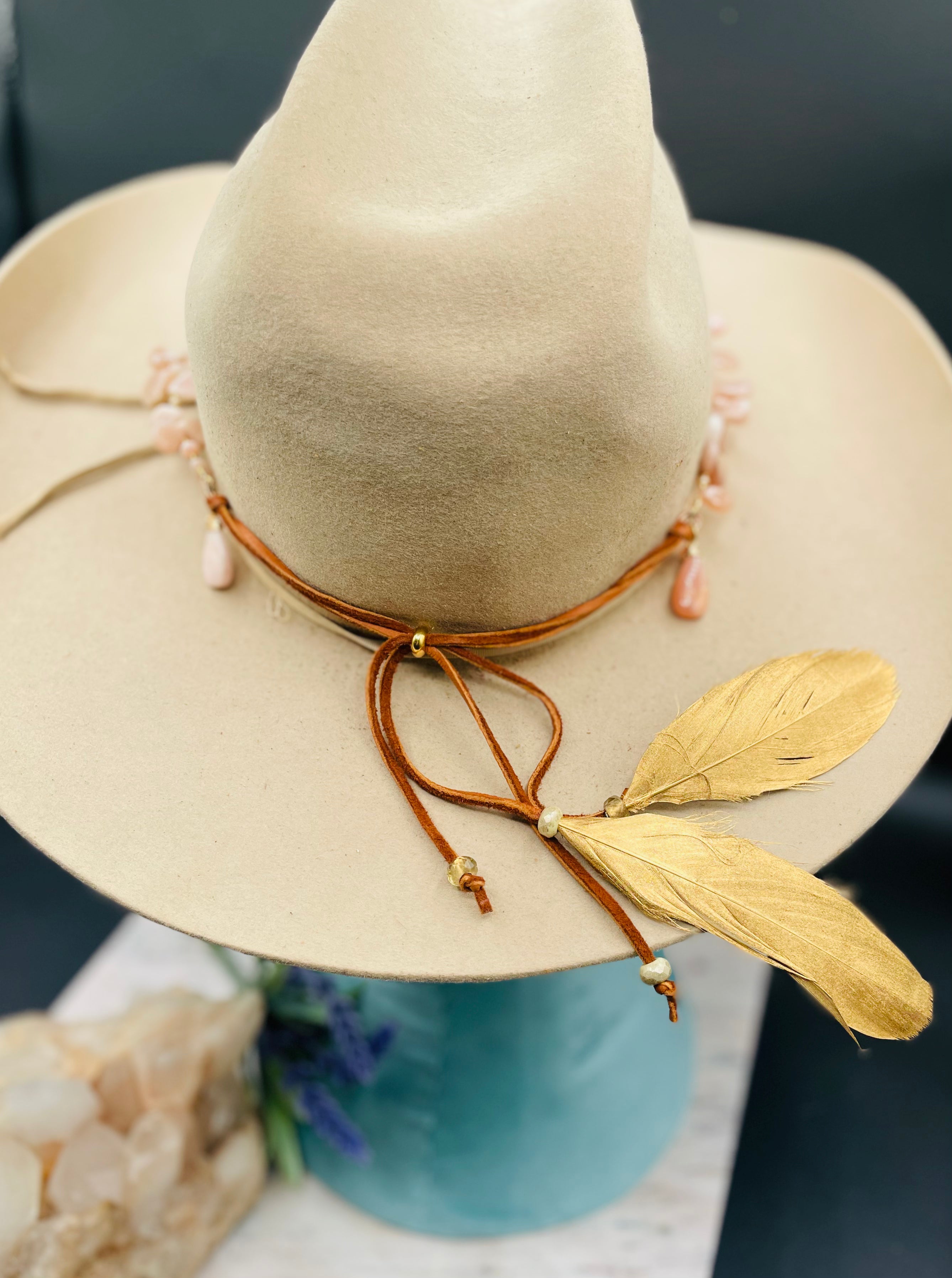 Close up of the gold painted feathers, glass beads, deer lace, and slide bead of this sunstone hatband or necklace. Available only from Rockstar Cowgirl online or in store in Cody, Wyoming