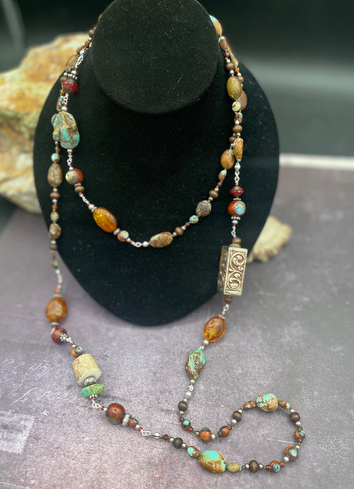 Long silk knotted and wire wrapped treasure necklace featuring #8 turquoise, Baltic amber, red travertine Czech beads, abalone inlaid wood beads, garnets, sterling silver beads, and deer antler beads and nuggets. Available only from Rockstar Cowgirl online or in store in Cody, Wyoming.