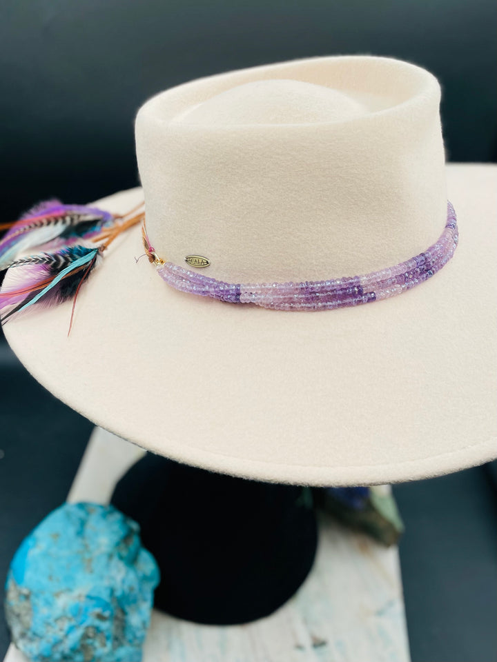 3 strand hatband or necklace of shaded amethyst with gold accents and finished with feathers, leather lace and a slide bead for fit. Available only from Rockstar Cowgirl online or in store in Cody, Wyoming.