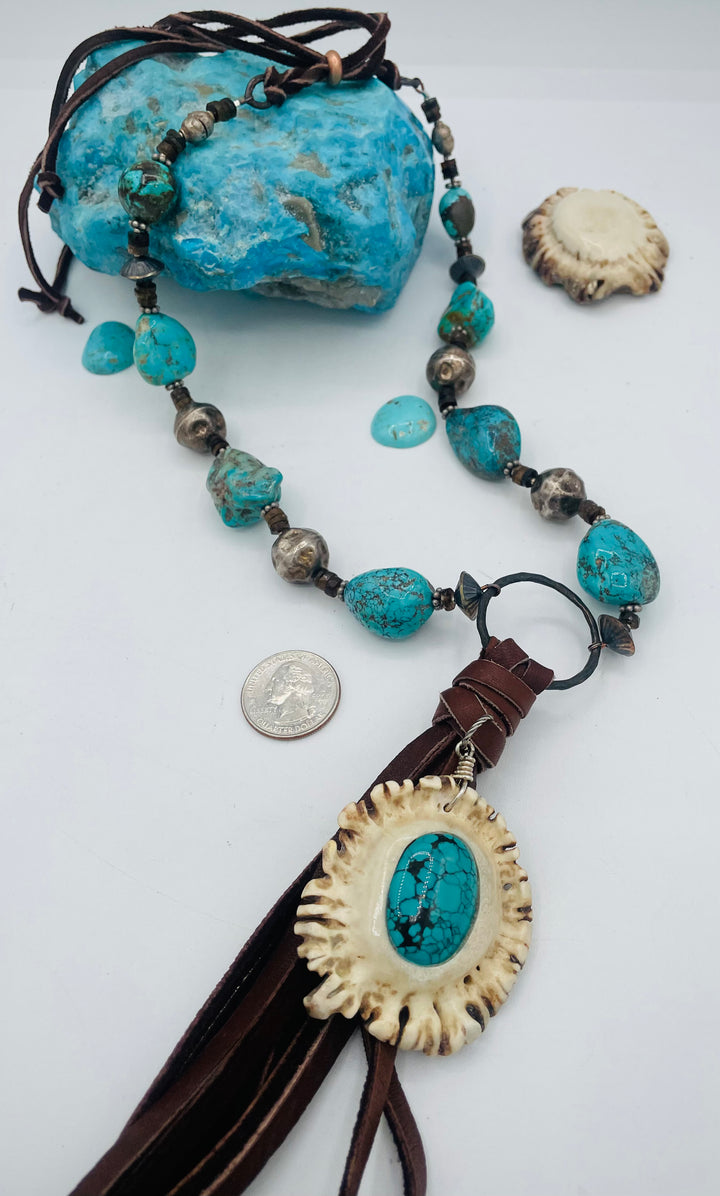 Adjustable beaded necklace featuring Kingman turquoise, hessonite garnet, vintage sterling silver, deer lace tassel with deer antler pendent, and finished with deer lace in the back. U.S. quarter for  size reference. Available only from Rockstar Cowgirl online or in store in Cody, Wyoming.