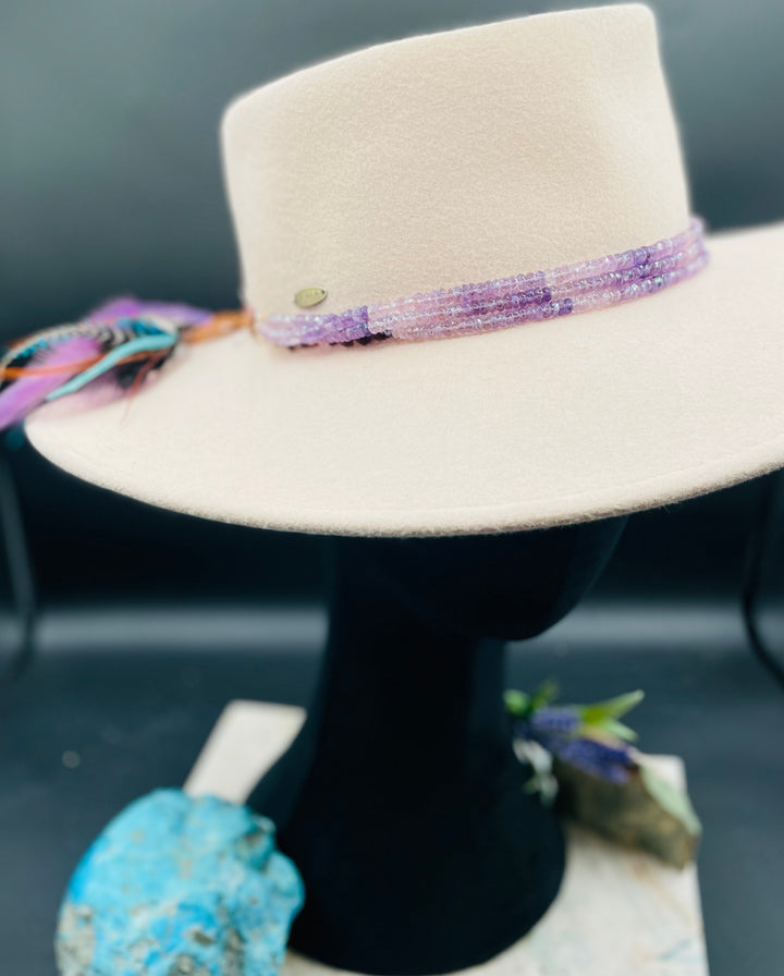 3 strand hatband or necklace of shaded amethyst with gold accents and finished with feathers, leather lace and a slide bead for fit. Available only from Rockstar Cowgirl online or in store in Cody, Wyoming.