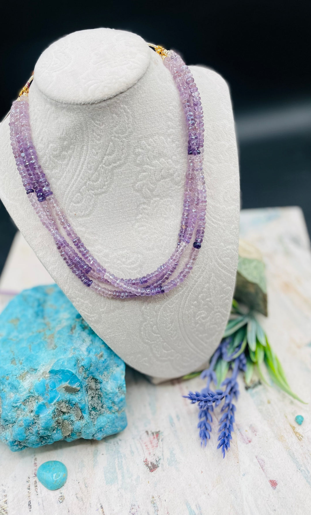 3 strand hatband or necklace of shaded amethyst with gold accents and finished with feathers, leather lace and a slide bead for fit. Available only from Rockstar Cowgirl online or in store in Cody, Wyoming.