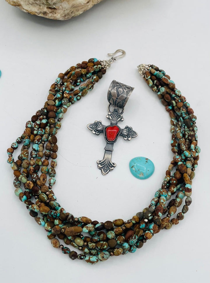 Beaded 7 strand necklace featuring #8 turquoise nuggets, sterling silver beads, with a coral and sterling silver cross pendent. Available only from Rockstar Cowgirl online or in store in Cody, Wyoming.