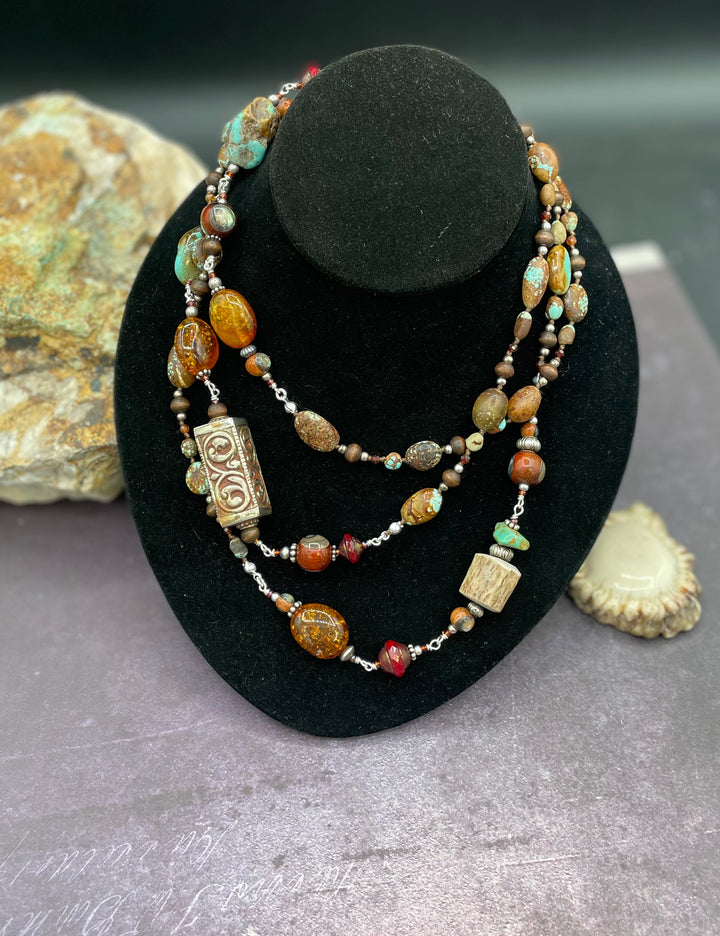 Long silk knotted and wire wrapped treasure necklace featuring #8 turquoise, Baltic amber, red travertine Czech beads, abalone inlaid wood beads, garnets, sterling silver beads, and deer antler beads and nuggets. Available only from Rockstar Cowgirl online or in store in Cody, Wyoming.