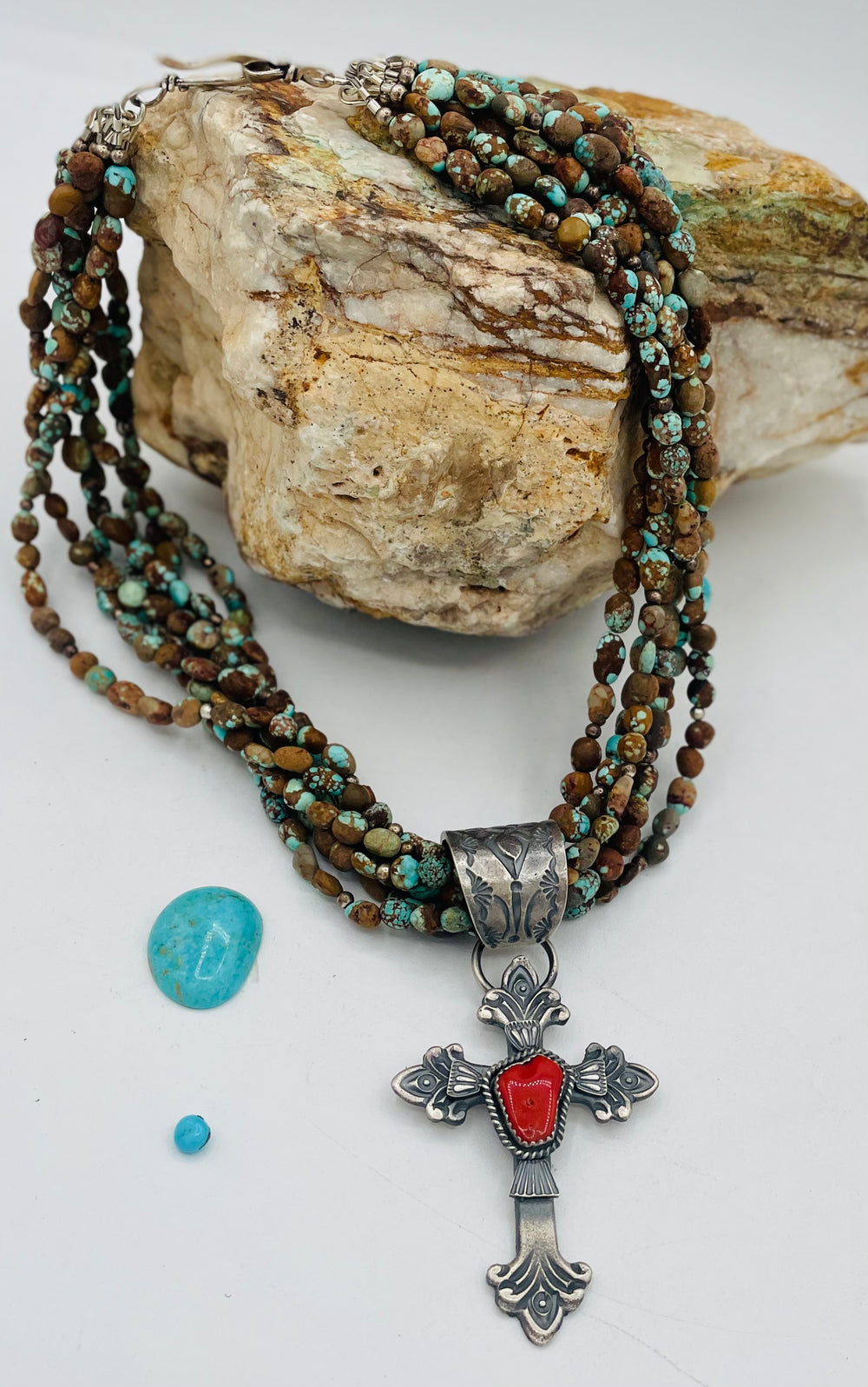 Beaded 7 strand necklace featuring #8 turquoise nuggets, sterling silver beads, with a coral and sterling silver cross pendent. Available only from Rockstar Cowgirl online or in store in Cody, Wyoming.