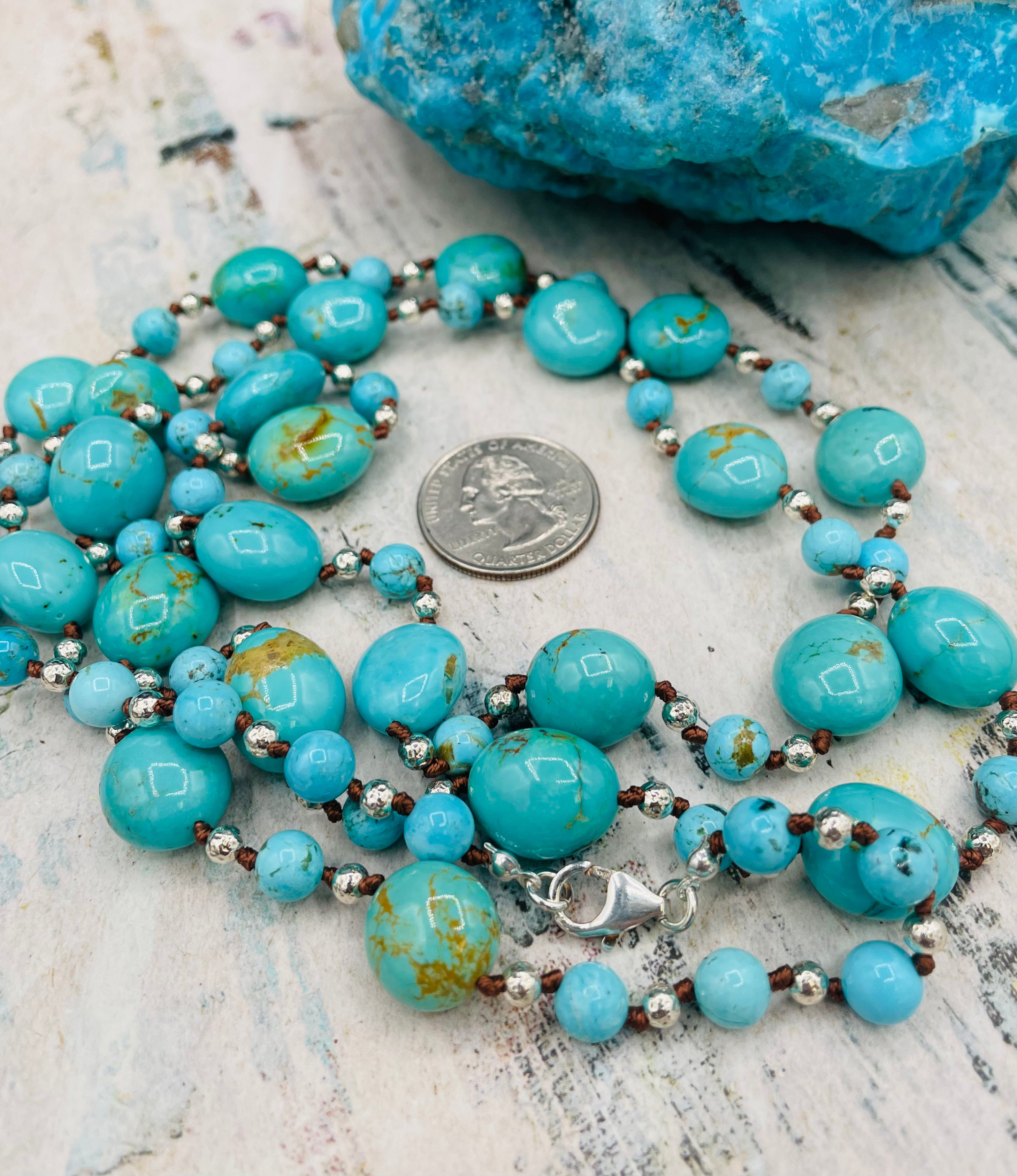 Long silk knotted necklace featuring Kingman turquoise nuggets and rounds with gold matrix, and hammered sterling silver beads. 
U.S. quarter for size reference. Available only from Rockstar Cowgirl online or in store in Cody, Wyoming.