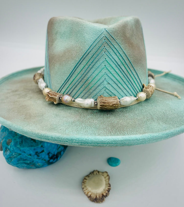 Adjustable beaded hattband featuring white flameball baroque pearls, textured deer antler, sterling silver beads, and finished with deer lace in the back. Available only from Rockstar Cowgirl online or in store in Cody, Wyoming.