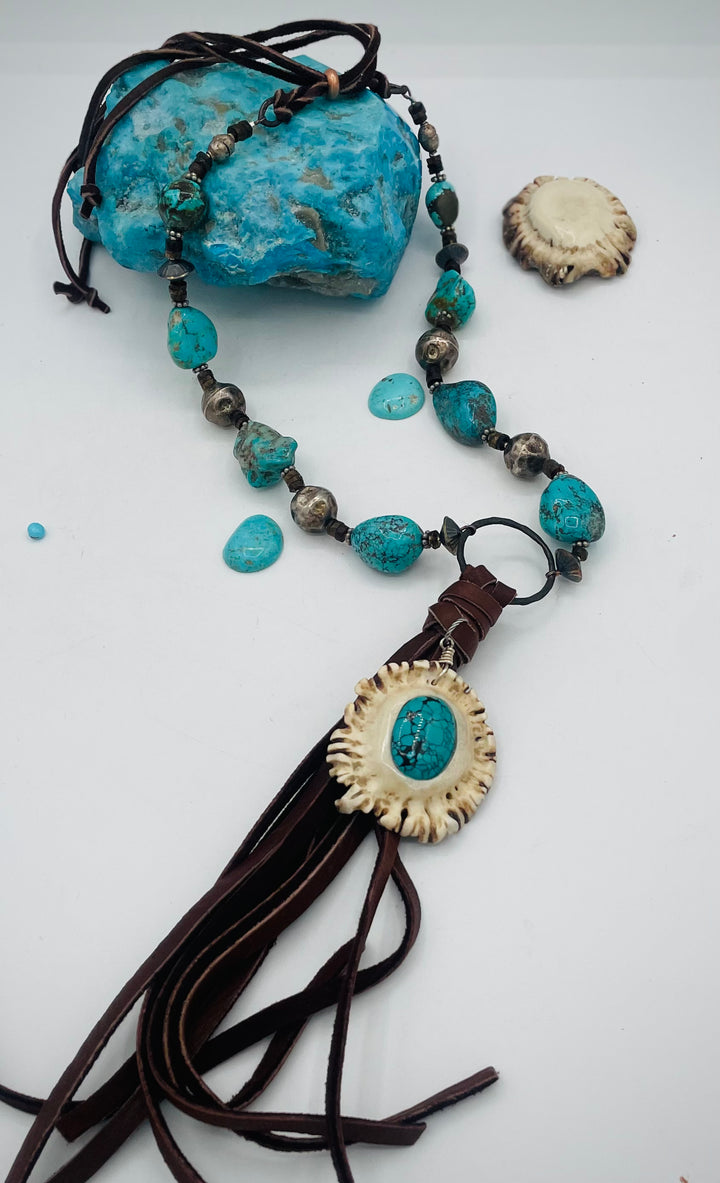 Adjustable beaded necklace featuring Kingman turquoise, hessonite garnet, vintage sterling silver, deer lace tassel with deer antler pendent, and finished with deer lace in the back. Available only from Rockstar Cowgirl online or in store in Cody, Wyoming.