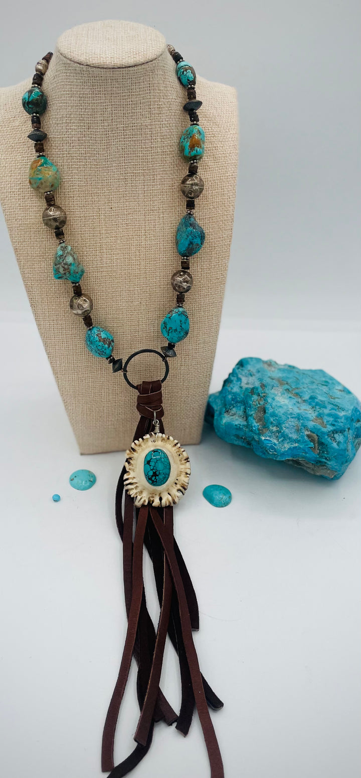 Adjustable beaded necklace featuring Kingman turquoise, hessonite garnet, vintage sterling silver, deer lace tassel with deer antler pendent, and finished with deer lace in the back. Available only from Rockstar Cowgirl online or in store in Cody, Wyoming.