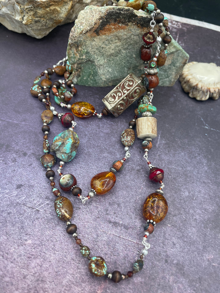 Long silk knotted and wire wrapped treasure necklace featuring #8 turquoise, Baltic amber, red travertine Czech beads, abalone inlaid wood beads, garnets, sterling silver beads, and deer antler beads and nuggets. Available only from Rockstar Cowgirl online or in store in Cody, Wyoming.