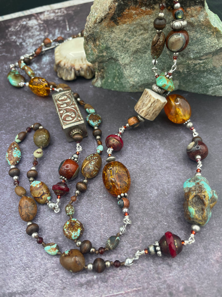 Long silk knotted and wire wrapped treasure necklace featuring #8 turquoise, Baltic amber, red travertine Czech beads, abalone inlaid wood beads, garnets, sterling silver beads, and deer antler beads and nuggets. Available only from Rockstar Cowgirl online or in store in Cody, Wyoming.